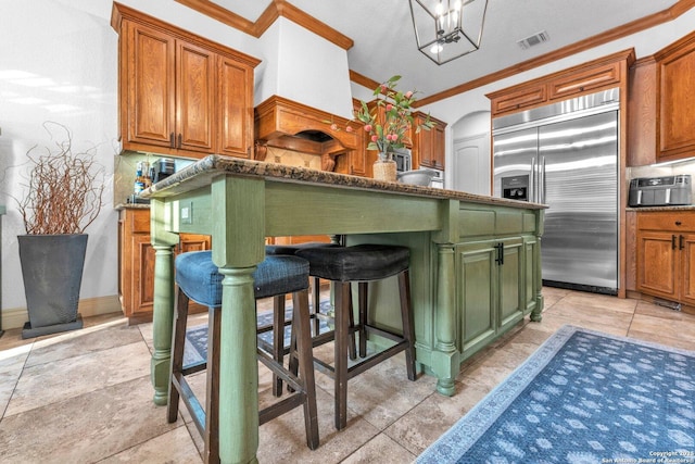 1015 Campanile, San Antonio, TX 78258 - kitchen featuring stainless steel built in refrigerator, crown molding, a breakfast bar area, green cabinets, and brown cabinetry