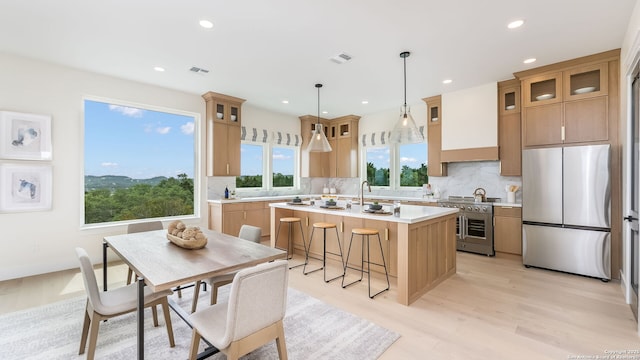 3140 Westview Dr, Canyon Lake, TX 78133 - kitchen with stainless steel appliances, an island with sink, light wood finished floors, light countertops, and tasteful backsplash