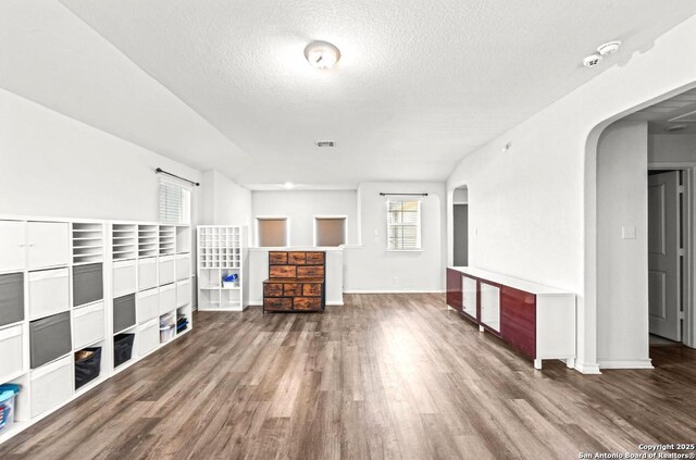 324 Washita Riv, Cibolo, TX 78108 - unfurnished living room with arched walkways, wood finished floors, a textured ceiling, and baseboards