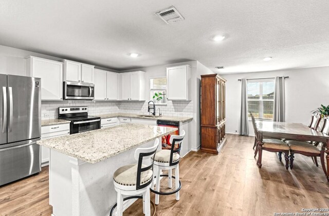 324 Washita Riv, Cibolo, TX 78108 - kitchen featuring appliances with stainless steel finishes, a sink, a center island, backsplash, and white cabinetry