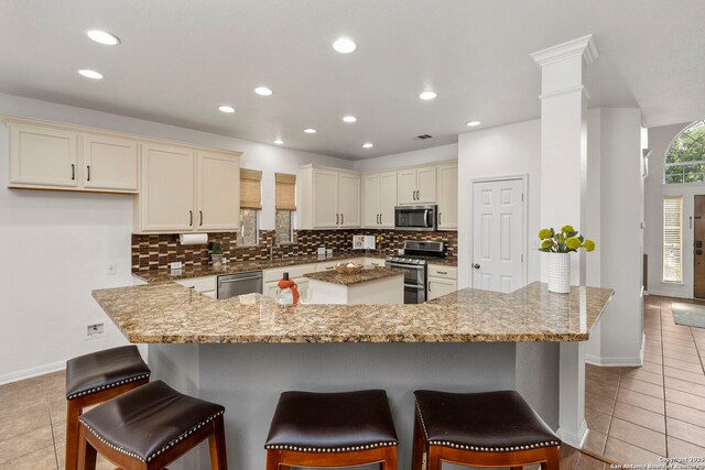 18719 Needle Rock, San Antonio, TX 78258 - kitchen with appliances with stainless steel finishes, a center island, light tile patterned flooring, tasteful backsplash, and baseboards