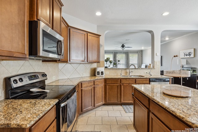 13508 Ashmont, Live Oak, TX 78233 - kitchen with stainless steel appliances, a sink, brown cabinetry, arched walkways, and recessed lighting