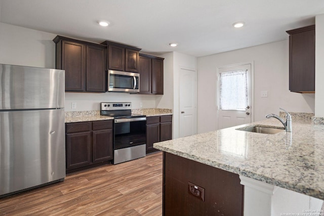 11042 Eyelet Hbr, Converse, TX 78109 - kitchen with appliances with stainless steel finishes, a sink, dark brown cabinets, wood finished floors, and light stone countertops