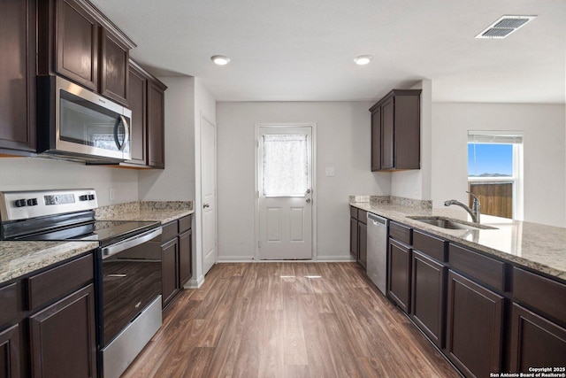 11042 Eyelet Hbr, Converse, TX 78109 - kitchen featuring appliances with stainless steel finishes, a sink, wood finished floors, dark brown cabinetry, and healthy amount of natural light