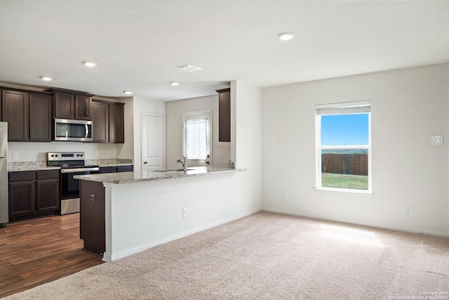 11042 Eyelet Hbr, Converse, TX 78109 - kitchen with stainless steel appliances, a sink, dark brown cabinets, dark carpet, and light stone counters