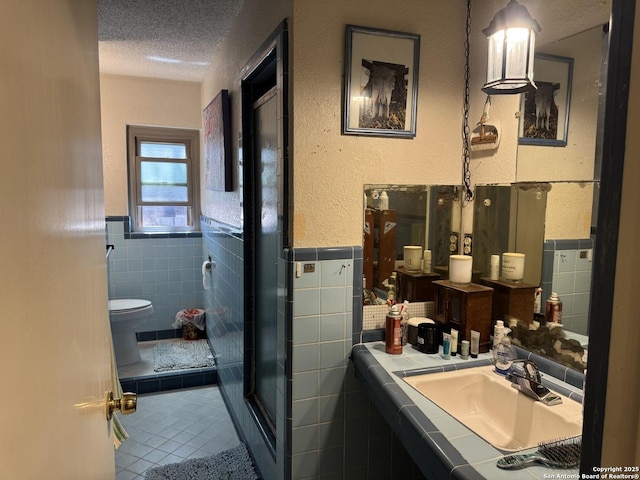 7084 Richter, Elmendorf, TX 78112 - bathroom featuring tile walls, a textured ceiling, tile patterned floors, toilet, and a sink