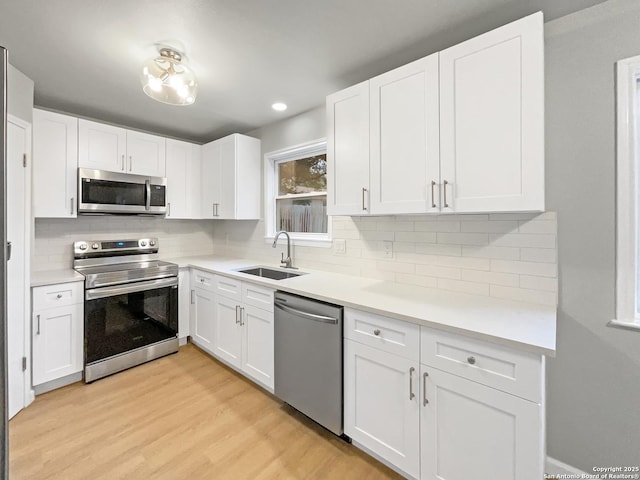 6218 Ridge Oak, San Antonio, TX 78250 - kitchen featuring stainless steel appliances, a sink, light wood-style flooring, white cabinetry, and recessed lighting