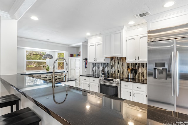 1946 Encino Belle, San Antonio, TX 78259 - kitchen featuring appliances with stainless steel finishes, ornamental molding, decorative backsplash, white cabinetry, and a kitchen breakfast bar
