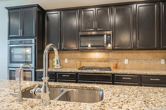 12827 Sabinal Riv, San Antonio, TX 78253 - kitchen with appliances with stainless steel finishes, decorative backsplash, light stone counters, and a sink