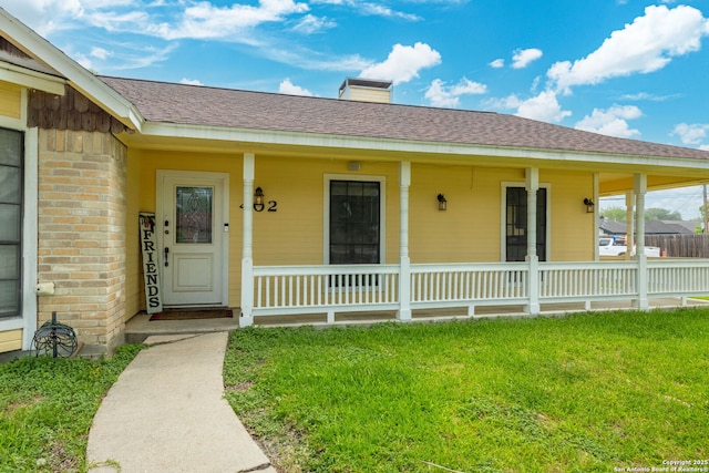 402 Teakwood, Victoria, TX 77901 - view of exterior entry with covered porch, a lawn, a chimney, and roof with shingles