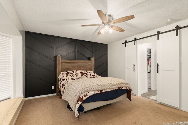 402 Teakwood, Victoria, TX 77901 - bedroom with a barn door, light carpet, ceiling fan, a textured ceiling, and baseboards