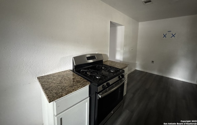 102 Killarney Dr, San Antonio, TX 78223 - kitchen with gas range, dark wood-style flooring, baseboards, dark stone countertops, and white cabinetry