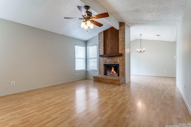 12215 Ridge Smt, San Antonio, TX 78247 - unfurnished living room with a ceiling fan, light wood-style flooring, a fireplace, a textured ceiling, and a chandelier