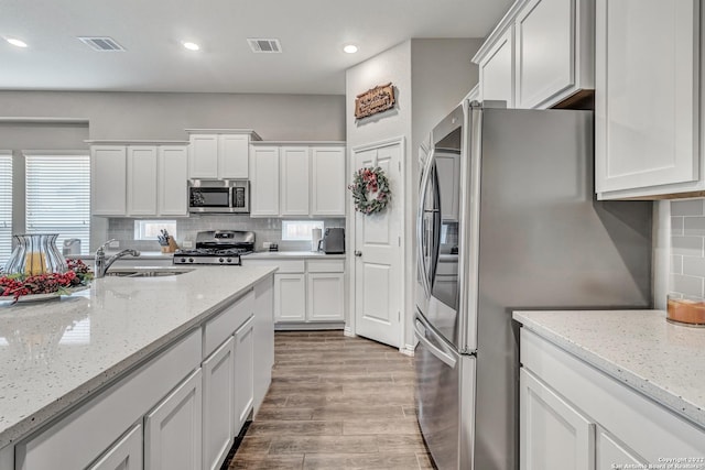 8922 Trail Dust, San Antonio, TX 78254 - kitchen with appliances with stainless steel finishes, a sink, white cabinets, backsplash, and light wood-style floors