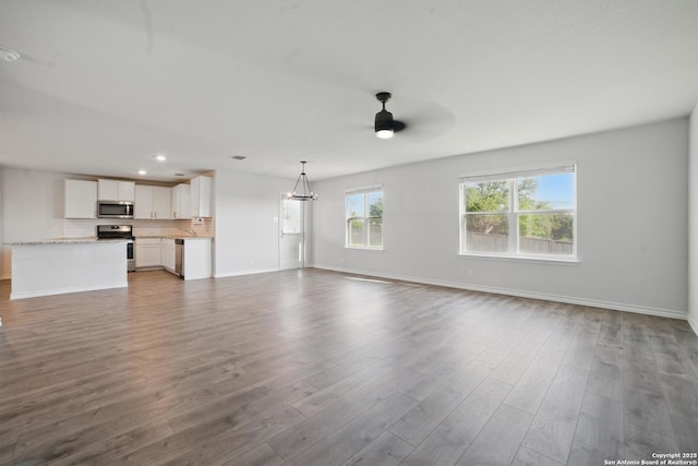 21902 Backspin, San Antonio, TX 78261 - unfurnished living room with ceiling fan, baseboards, wood finished floors, recessed lighting, and a chandelier
