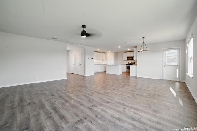 21902 Backspin, San Antonio, TX 78261 - unfurnished living room featuring wood finished floors, recessed lighting, a chandelier, ceiling fan, and baseboards