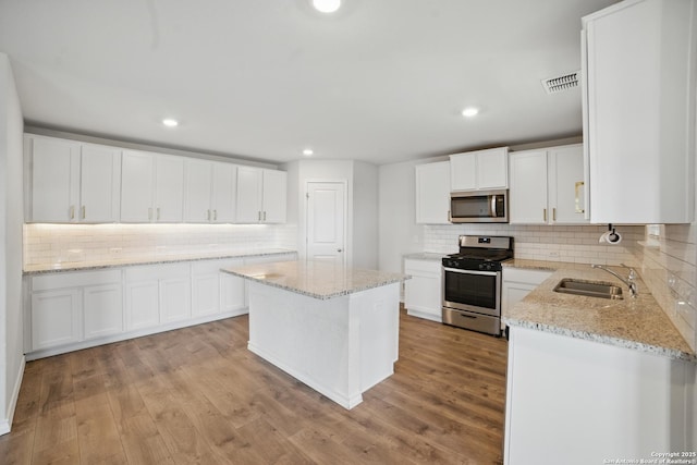 21902 Backspin, San Antonio, TX 78261 - kitchen with appliances with stainless steel finishes, a sink, tasteful backsplash, light stone countertops, and light wood-type flooring