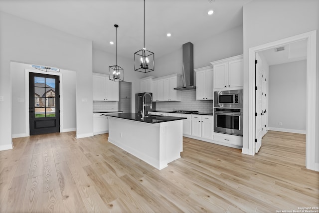 190 Azalea Aly, Castroville, TX 78009 - kitchen featuring appliances with stainless steel finishes, dark countertops, wall chimney exhaust hood, backsplash, and a chandelier