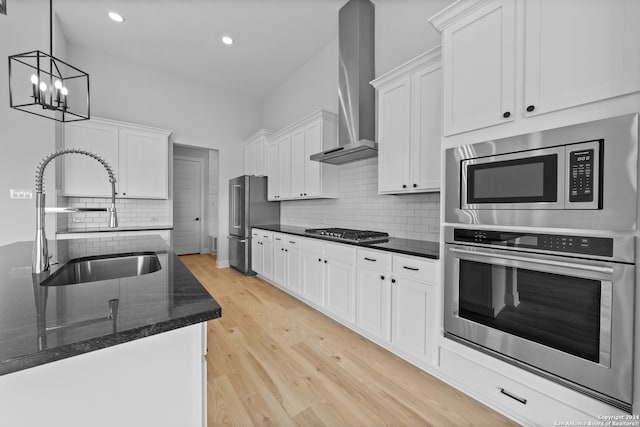 190 Azalea Aly, Castroville, TX 78009 - kitchen featuring stainless steel appliances, a sink, wall chimney range hood, light wood finished floors, and white cabinets