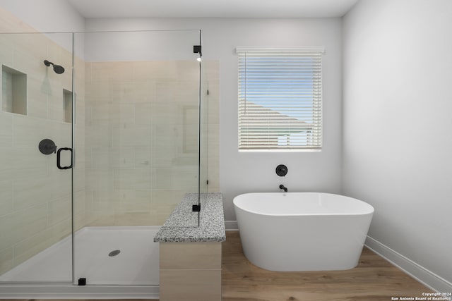 204 Azalea Aly, Castroville, TX 78009 - bathroom with a stall shower, a freestanding tub, wood finished floors, and baseboards