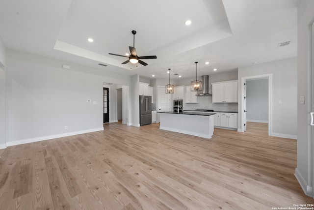 204 Azalea Aly, Castroville, TX 78009 - kitchen featuring wall chimney range hood, open floor plan, dark countertops, a tray ceiling, and recessed lighting