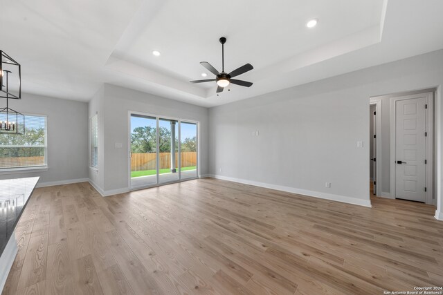 204 Azalea Aly, Castroville, TX 78009 - unfurnished living room with a tray ceiling, light wood-style floors, ceiling fan, baseboards, and recessed lighting