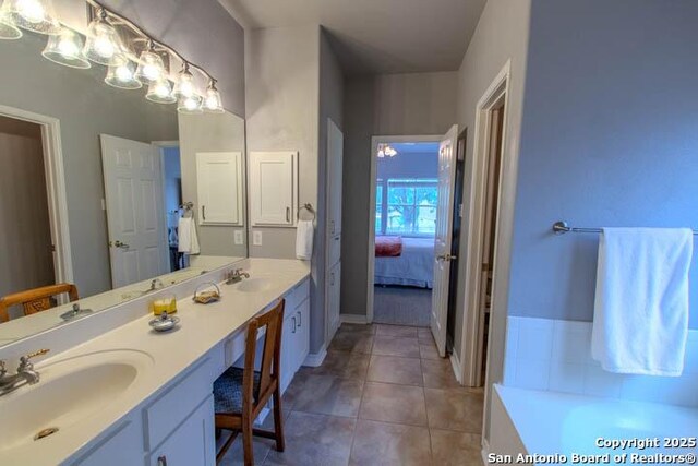 228 Long Crk, New Braunfels, TX 78130 - ensuite bathroom featuring double vanity, tile patterned flooring, a bathtub, and baseboards