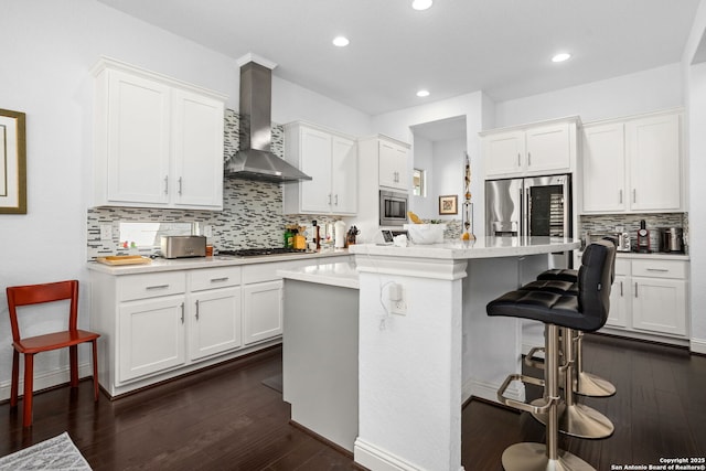 17 Denbury, San Antonio, TX 78257 - kitchen featuring wall chimney range hood, appliances with stainless steel finishes, tasteful backsplash, a breakfast bar area, and recessed lighting