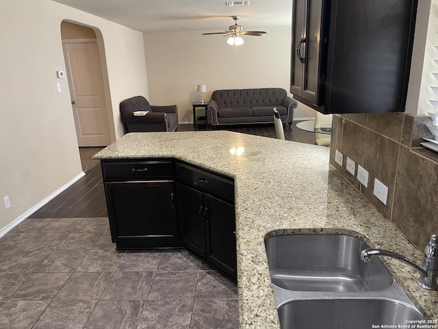 12242 Bening Vly, Schertz, TX 78154 - kitchen featuring a sink, a ceiling fan, dark cabinetry, open floor plan, and arched walkways