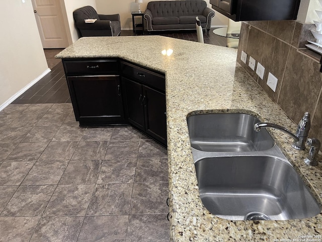 12242 Bening Vly, Schertz, TX 78154 - kitchen featuring a sink, light stone countertops, baseboards, dark cabinetry, and tasteful backsplash