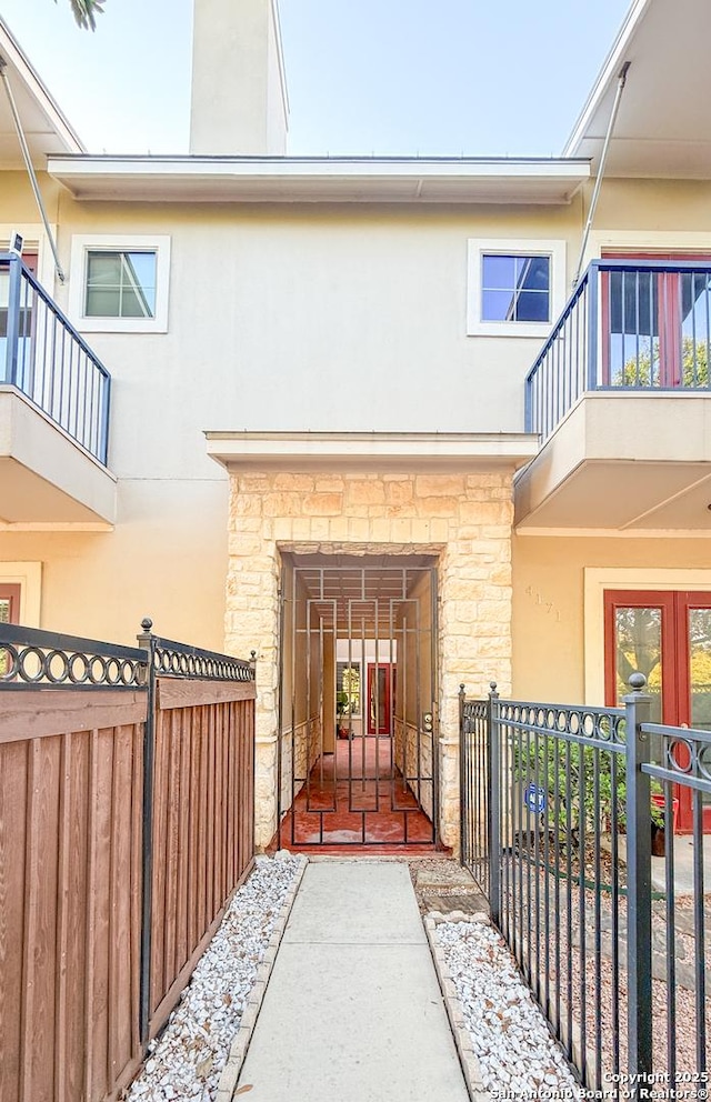 4171 Texas Elm, San Antonio, TX 78230 - view of exterior entry featuring stone siding, a balcony, stucco siding, and a gate