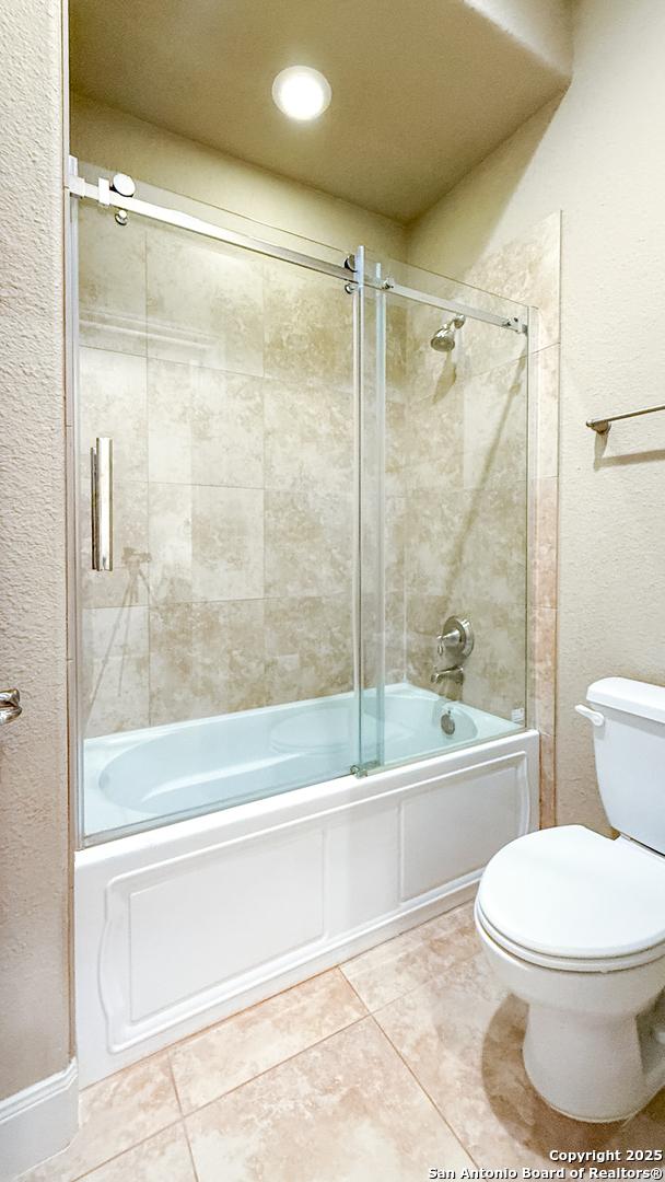 4171 Texas Elm, San Antonio, TX 78230 - bathroom featuring tile patterned floors, enclosed tub / shower combo, toilet, and a textured wall