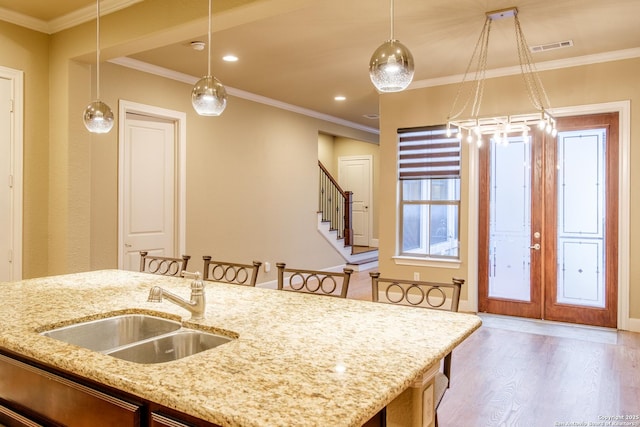 4171 Texas Elm, San Antonio, TX 78230 - kitchen featuring a sink, wood finished floors, decorative light fixtures, ornamental molding, and light stone counters