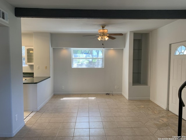 1076 Eastview, Canyon Lake, TX 78133 - unfurnished living room featuring ceiling fan, plenty of natural light, light tile patterned floors, beam ceiling, and baseboards