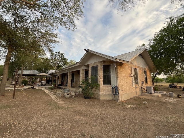 512 Brown Ln, Floresville, TX 78114 - view of home's exterior featuring brick siding, metal roof, a patio area, and central air condition unit