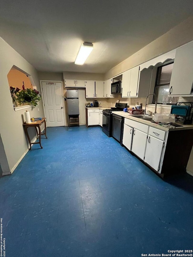 512 Brown Ln, Floresville, TX 78114 - kitchen with black appliances, a sink, white cabinetry, baseboards, and dark flooring