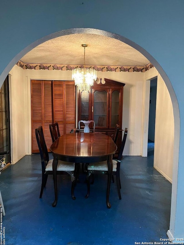 512 Brown Ln, Floresville, TX 78114 - dining area featuring a chandelier, concrete flooring, arched walkways, and a textured ceiling