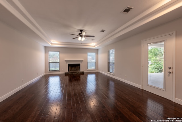 8718 Paseo Oaks, San Antonio, TX 78255 - unfurnished living room with a tray ceiling, ceiling fan, dark wood-style floors, a fireplace with raised hearth, and baseboards