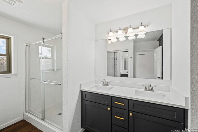 1312 Acorn, Hondo, TX 78861 - bathroom featuring a shower stall, double vanity, wood finished floors, and baseboards