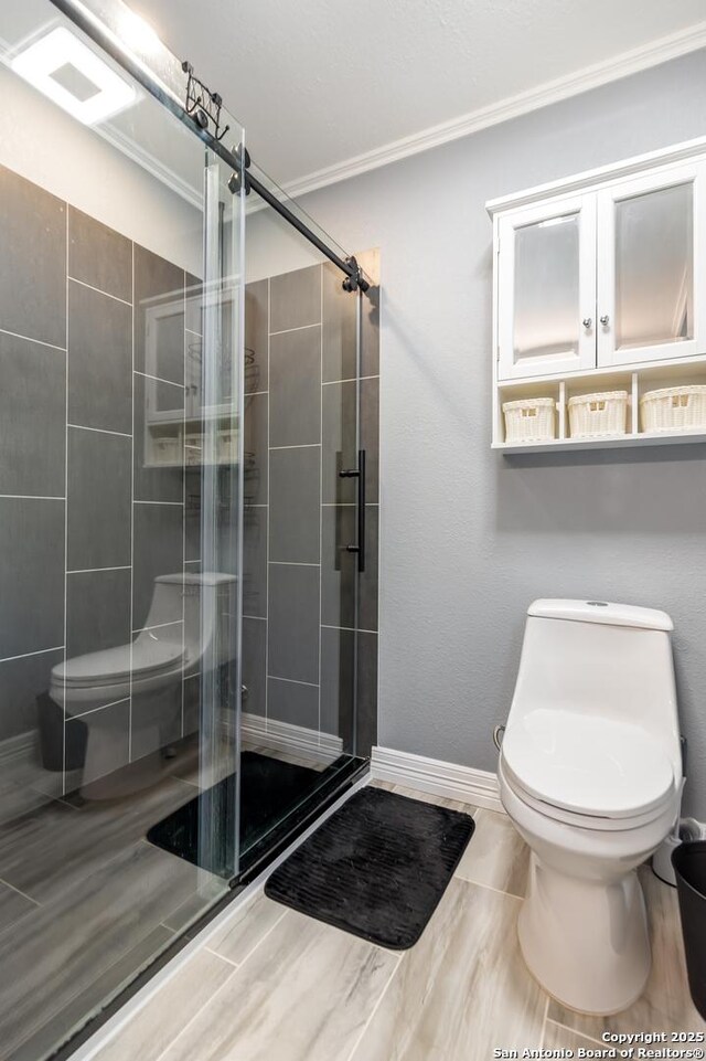 1556 County Road 2537, Moore, TX 78057 - full bathroom with toilet, crown molding, a shower stall, and baseboards
