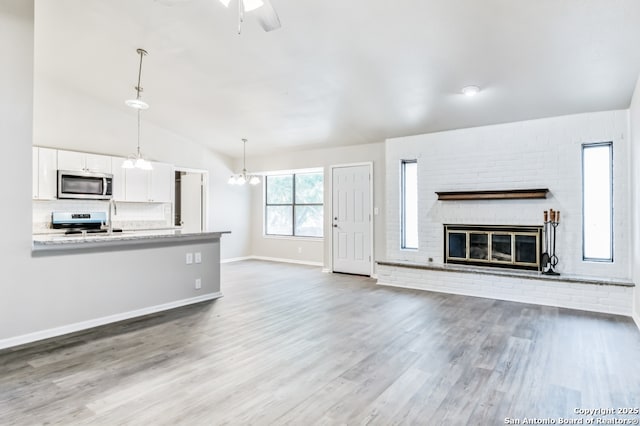 4203 Quail, San Antonio, TX 78217 - unfurnished living room featuring lofted ceiling, a chandelier, wood finished floors, baseboards, and a fireplace