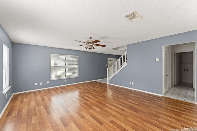 8134 Cheryl Mdw, Converse, TX 78109 - spare room featuring light wood-type flooring, stairs, a ceiling fan, a textured ceiling, and baseboards