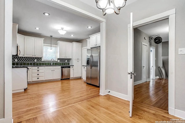436 W Gramercy Pl, San Antonio, TX 78212 - kitchen featuring appliances with stainless steel finishes, dark countertops, light wood-type flooring, decorative backsplash, and a chandelier