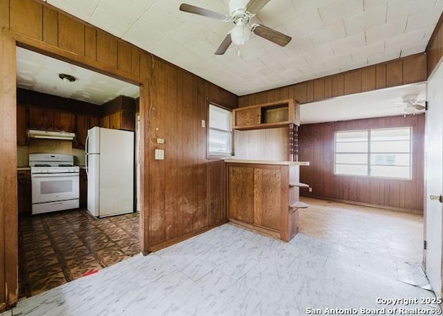 36 County Road 346c, Shiner, TX 77984 - kitchen featuring white appliances, under cabinet range hood, a ceiling fan, wooden walls, and healthy amount of natural light
