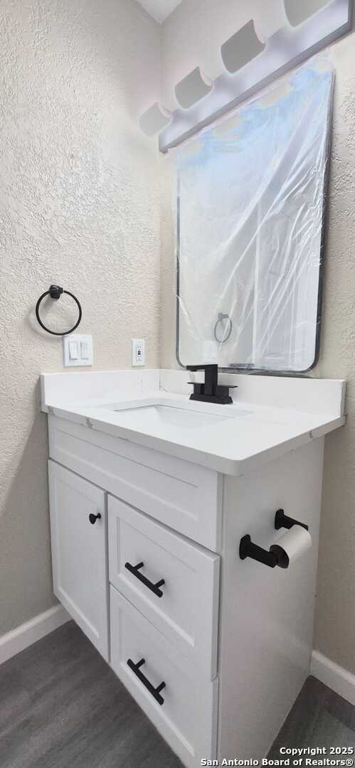 6115 Calderwood St, San Antonio, TX 78249 - bathroom with vanity, baseboards, a textured wall, and wood finished floors