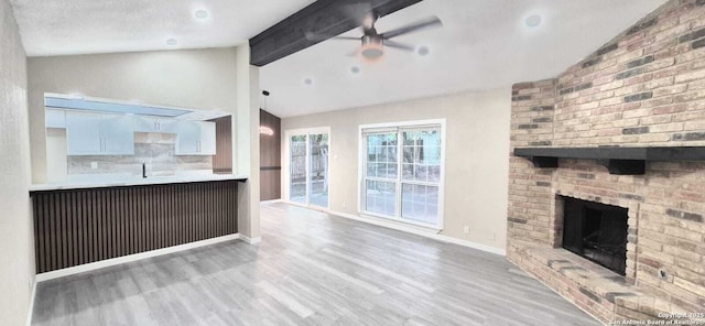 6115 Calderwood St, San Antonio, TX 78249 - unfurnished living room featuring wood finished floors, a ceiling fan, a brick fireplace, beam ceiling, and baseboards