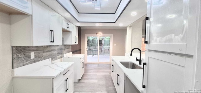 6115 Calderwood St, San Antonio, TX 78249 - kitchen featuring a sink, light wood-type flooring, white cabinetry, and a raised ceiling