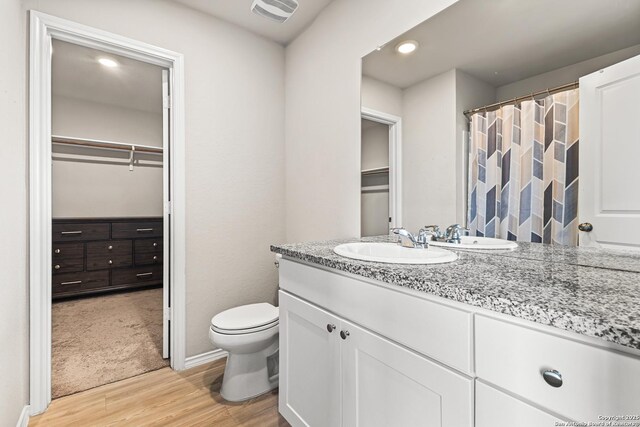 7207 Lincoln Trce, San Antonio, TX 78222 - full bathroom featuring wood finished floors, vanity, a walk in closet, toilet, and recessed lighting
