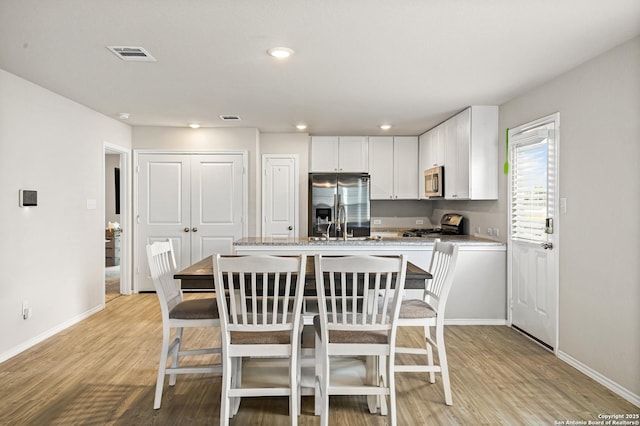 7207 Lincoln Trce, San Antonio, TX 78222 - kitchen featuring appliances with stainless steel finishes, white cabinetry, light wood-style floors, baseboards, and recessed lighting