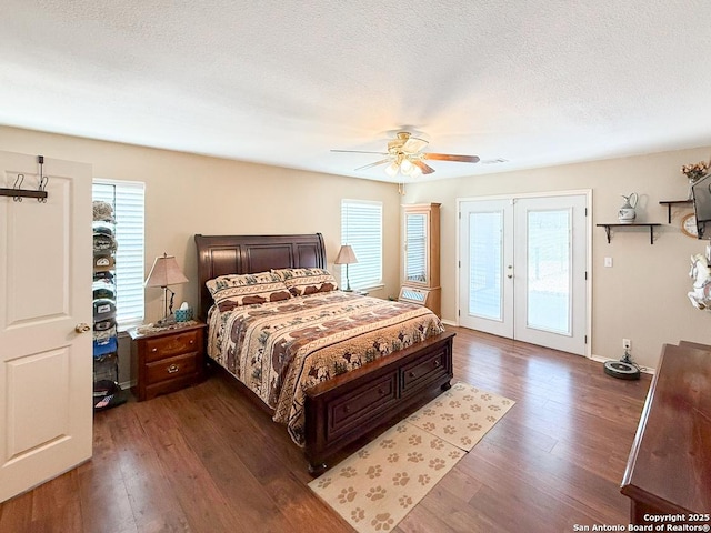 1185 County Road 7718, Devine, TX 78016 - bedroom featuring access to outside, dark wood-type flooring, multiple windows, french doors, and a textured ceiling